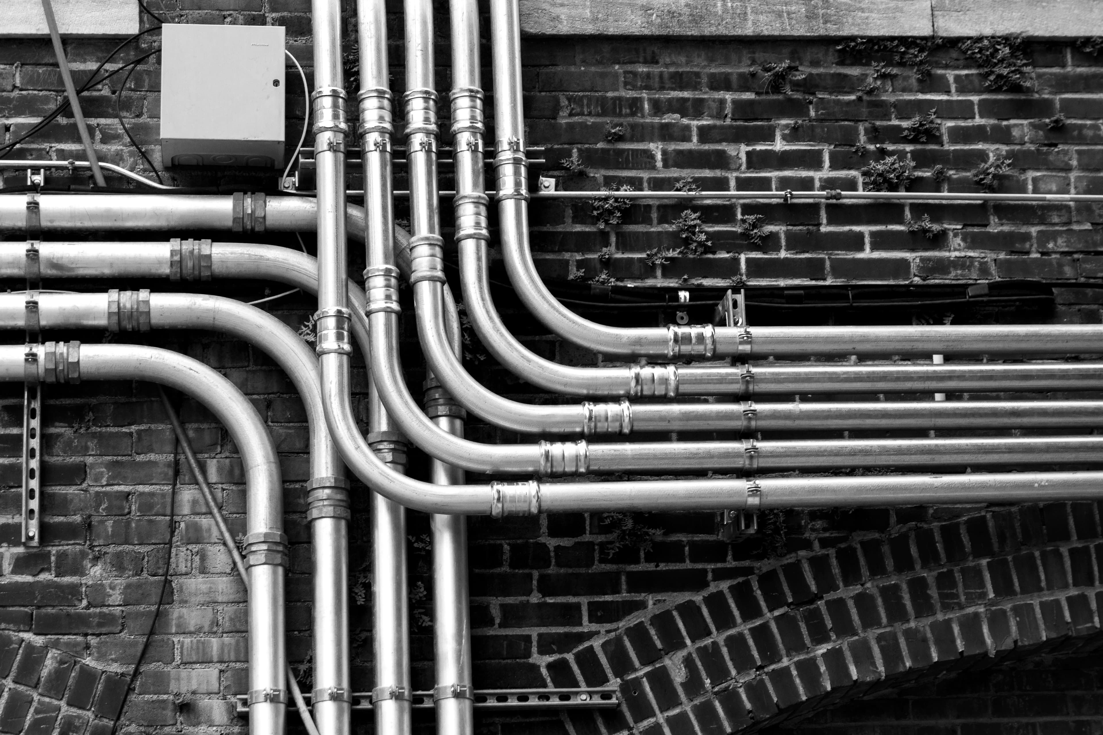 Network of exposed plumbing pipes neatly installed on a wall